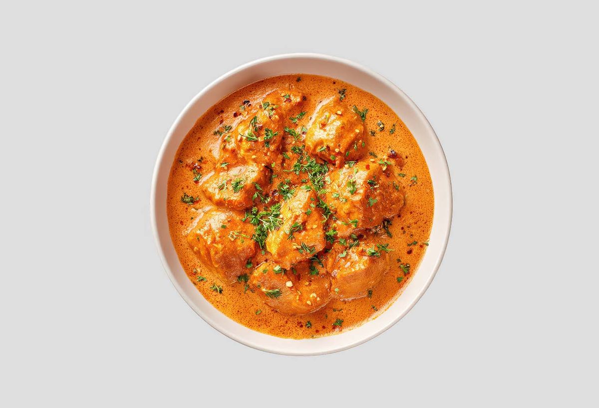 Creamy lamb tikka masala served in a bowl, featured as a must-try dish.