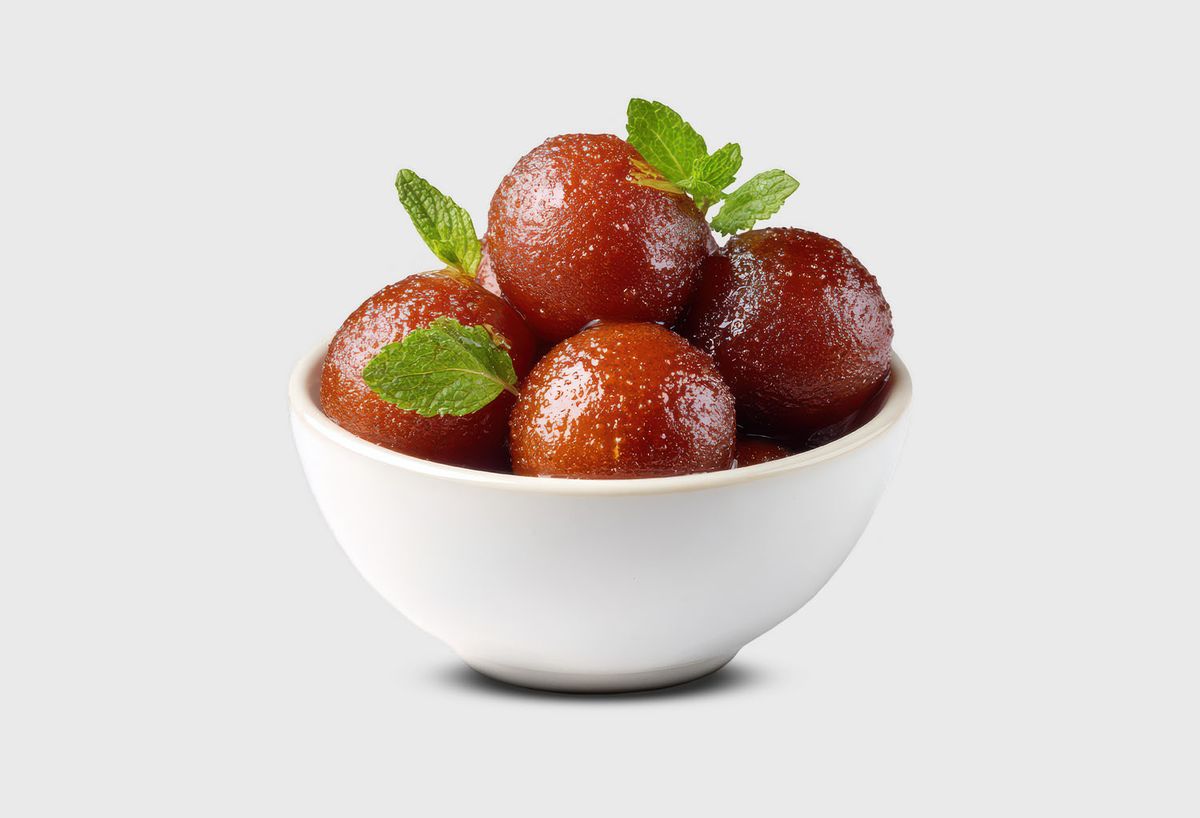 Gulab jamun and rasmalai served in bowls, featured in a blog about Indian desserts.