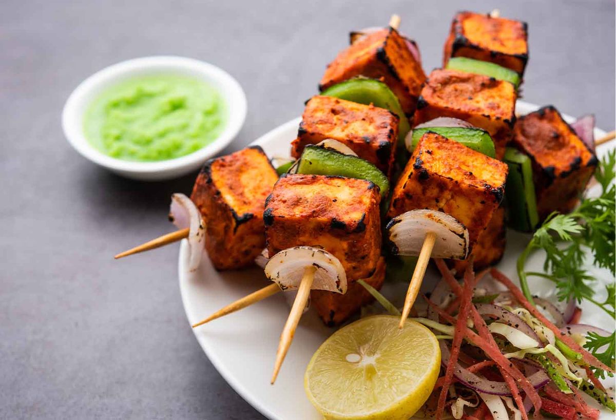 Grilled paneer tikka with spices, highlighted as a must-try vegetarian dish.